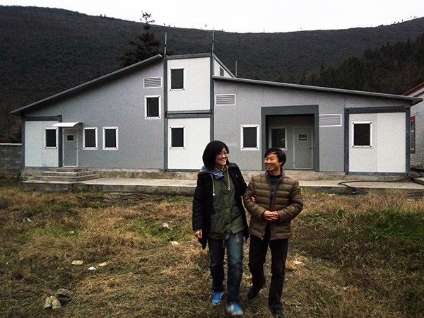 Liu and a teacher in front of a Flying Box dormitory in the school. (Provided to CHINA DAILY)