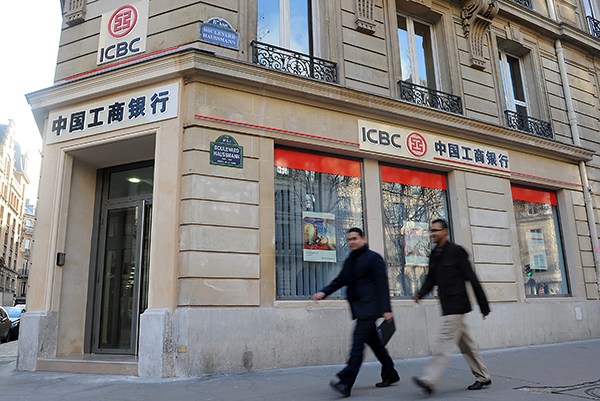 Two people pass by the branch of Industrial & Commercial Bank of China (ICBC) in Paris, France. (Paul Boursier/For China Daily)