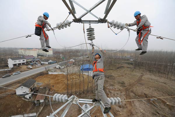 Workers fasten electric wires in a rural area in Chuzhou, Anhui province. (Song Weixing/For China Daily)