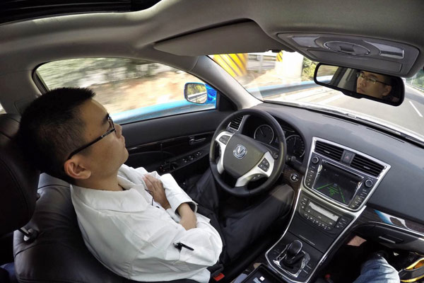 Engineers watch videos on their smartphones during a test journey from Chongqing in southwestern China to Beijing in April. The car used was an autonomous sedan developed by Chang'an Automobile Group. (Photo/China Daily)