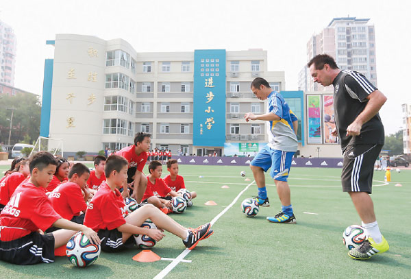 Tom Byer (right), an international soccer coach, teaches primary school pupils in Beijing. (Photo provided to China Daily)