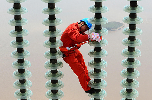 A worker from State Grid repairs power transmission facilities in Zhoushan, Zhejiang province. (Yao Feng/For China Daily)