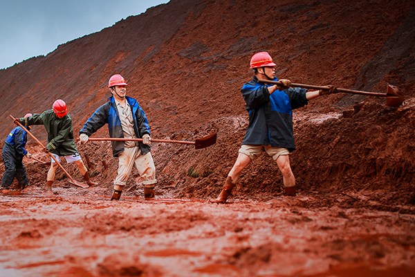 Workers of Magang (Group) Holding Co Ltd clear a cave-in of raw materials, caused by continuous rainstorms, in Ma'anshan, Anhui province. (Photo/China Daily)