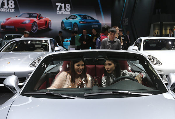 Potential buyers try a new car at an auto expo in Beijing.(Photo:China Daily/Wang Zhuangfei)