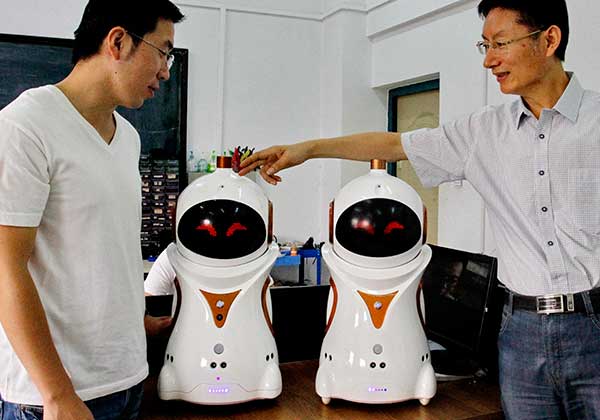 Professor Zhou Fengyu (right) displays the newly developed robots with his colleague.(Ju Chuanjiang/China Daily)