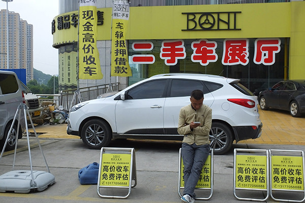A man sits outside a used car dealership in Yichang, Hubei province. (Photo provided to China Daily)