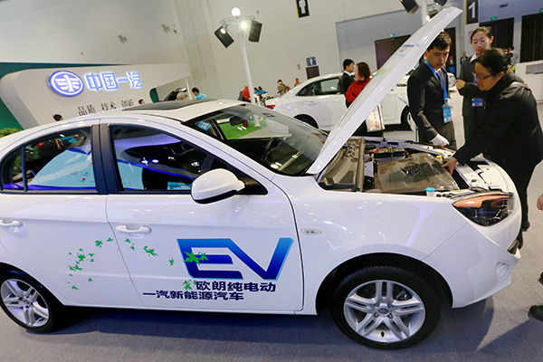 Visitors examine a pure electric car at an auto exhibition in Beijing late last year. (Photo provided to China Daily)