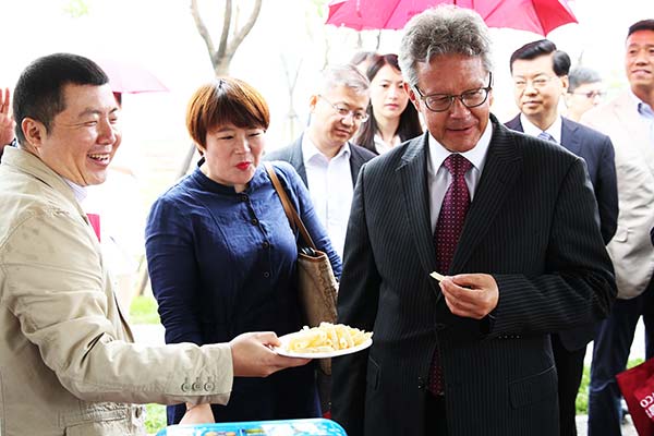 Ronald Keller, Dutch ambassador to China, tastes food at an exhibition in Beijing organized by China National Cereals, Oils and Food-stuffs Corp, a major State enterprise in China.(Provided to China Daily)