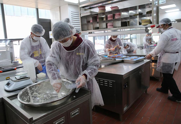 Some workers produce food in a kitchen at Hema Waimai in Shanghai on March 17, 2016. (Photo/Xinhua)