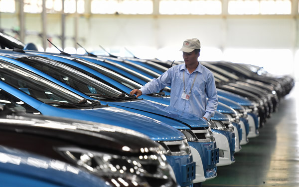 A worker checks electric vehicles made by BYD Co Ltd at the company's headquarters in Shenzhen, Guangdong province. (Photo/Xinhua)