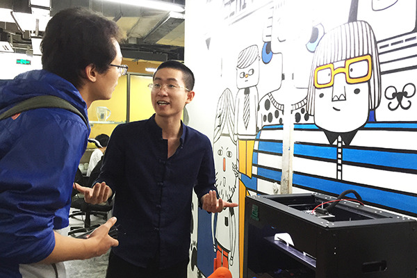 An owner of a startup in Dream Village, Hangzhou, explains his firm's business to a visiting journalist. (Photo/China Daily)