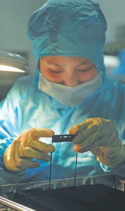 A worker tests smartphone glass cover at a Lens Technology Co Ltd plant in Liuyang, Hunan province. The Apple Inc supplier is targeting Chinese phone makers to shore up its sales. )Photo/China Daily)