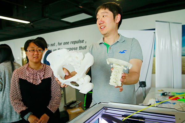 A man shows 3D printed copies of parts of human cervical spine and pelvis during a recent launch of an innovation center in Tianjin. (Photo/China Daily)