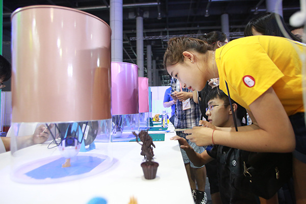 Visitors watch a working 3D printer at a recent technology innovation expo in Dalian, Liaoning province. (Photo/China Daily)
