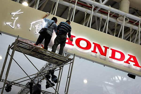 Workers decorate the Dongfeng Hongda exhibiting area at an auto show in Fuzhou, Fujian province. (Photo/China Daily)