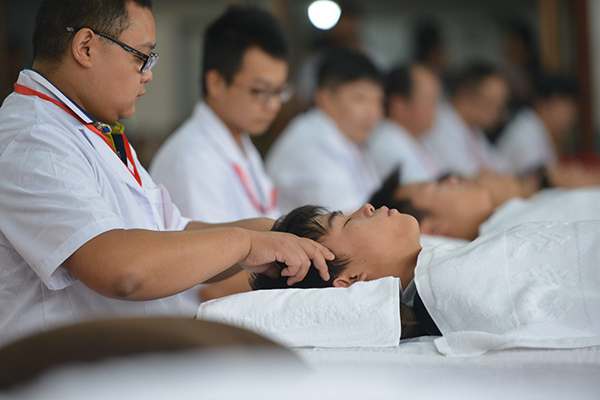 Students practise point massage, a traditional Chinese medical care solution to relieve patients' headache during a TCM training in Chengdu, Sichuan province. (Photo/China Daily) 