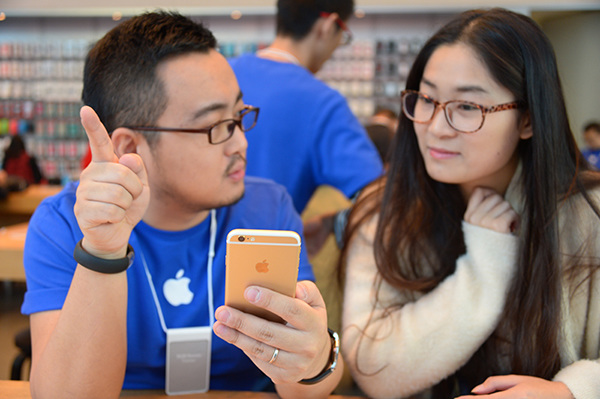 A salesman demonstrates an iPhone 6 during its launch in Beijing in October 2014. (Photo/China Daily)