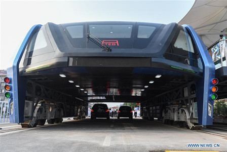 The transit elevated bus TEB-1 is on road test in Qinhuangdao, north China's Hebei Province, Aug. 2, 2016. China's home-made transit elevated bus, TEB-1, conducted a road test running Tuesday. The 22-meter-long, 7.8-meter-wide and 4.8-meter-high TEB-1 can carry up to 300 passengers. The passenger compartment of this futuristic public bus rises far above other vehicles on the road, allowing cars to pass underneath. (Xinhua/Luo Xiaoguang)