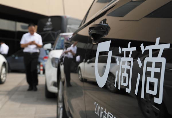 A pedestrian passes by a chauffeured car of Didi Chuxing, the dominant ride-hailing service provider in China. (Wu Changqing / for China Daily)