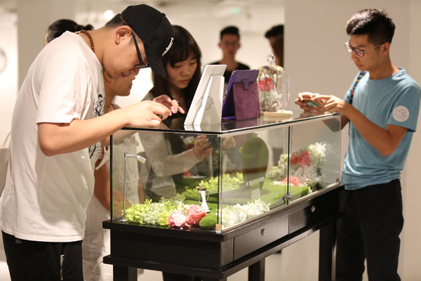 Visitors take photos of smart jewelry at the launch of the Totwoo brand in late July in Beijing. (PROVIDED TO CHINA DAILY)