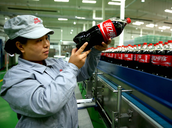 An employee of a COFCO Coca-Cola venture checks the packaging quality of drinks in a plant in Shijiazhuang, Hebei province. (Photo/Xinhua)