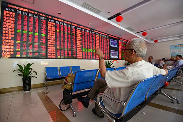 An investor checks stock prices at a securities brokerage in Fuyang, Anhui province.(Lu Qijian / for China Daily)