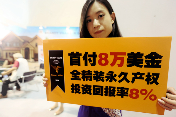 A girl holds a billboard to promote overseas homes at a realty expo in Beijing. A Qing / For China Daily