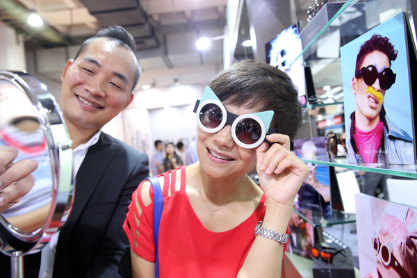 A visitor tries on a stylish UV-light protective glasses at an international optometric and optical fair in Beijing. (CHEN XIAOGEN/CHINA DAILY)