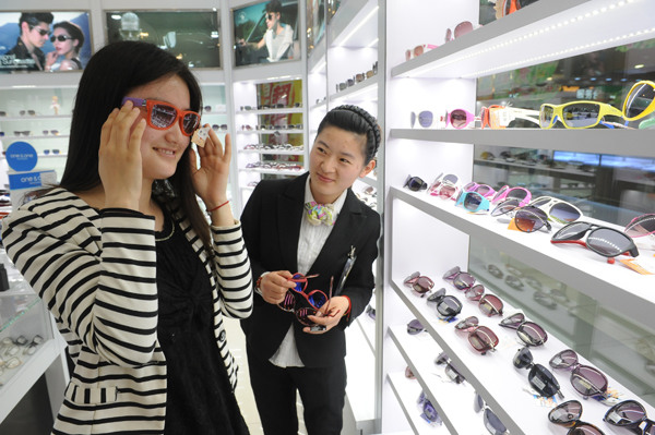 A young woman chooses sunglasses in a store in Fuyang, East China's Anhui province. (PHOTO PROVIDED TO China Daily)