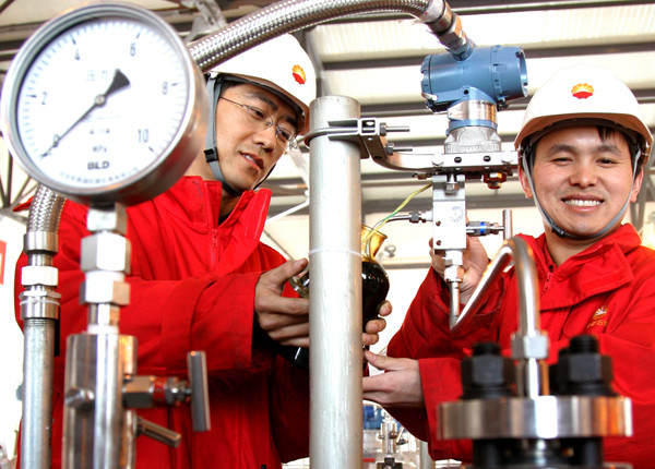 Two China National Petroleum Corp employees collect crude oil transported from Russia at the valve chamber in Daqing, Heilongjiang province.(GUO JUNFENG/FOR CHINA DAILY)