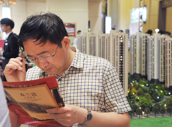 A potential homebuyer checks realty brochures at a property expo in Shanghai. Provided to China Daily