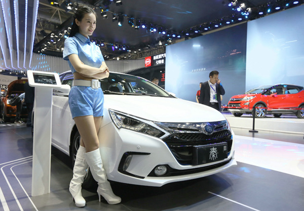 A model stands beside a BYD car at an auto expo in Beijing. A JING/FOR CHINA DAILY