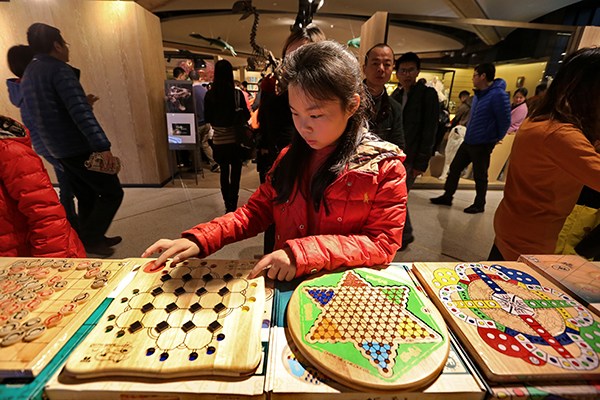 A girl tries her fingers at a chess-like board game designed to develop children's intelligence, at an Eslite bookstore in Suzhou, Jiangsu province. (Photo/China Daily)