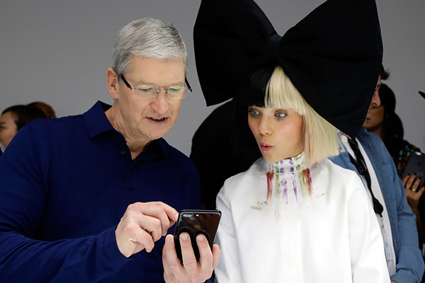 Apple CEO Tim Cook shows an iPhone 7 to performer Maddie Ziegler during an event to announce new products on Wednesday in San Francisco. (Photo provided to China Daily)
