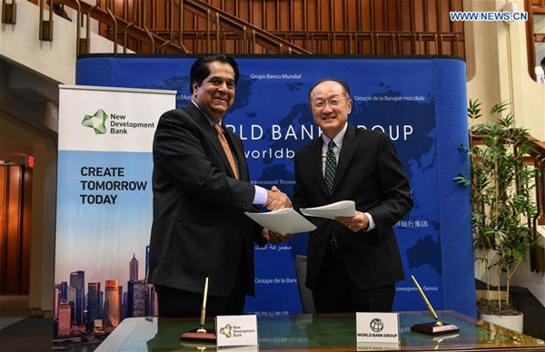 World Bank Group President Jim Yong Kim (R) and New Development Bank President K.V. Kamath shake hands after signing a memorandum in Washington D.C., the United States, Sept. 9, 2016.(Xinhua/Bao Dandan)