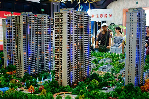 Potential homebuyers examine a property project model in Yichang, Hubei province, Aug 23, 2016. (Photo/China Daily)