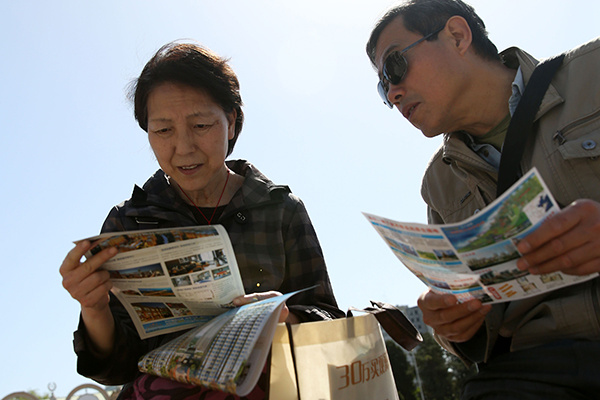 Potential homebuyers read advertisements at a property expo in Beijing in April. (Photo/China Daily)
