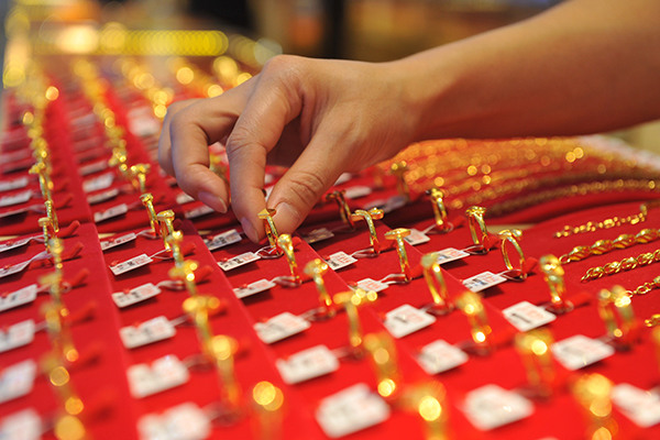 A clerk sorts gold jewelry at a shop in Linan, Zhejiang province, June, 25. (Photo/China Daily)