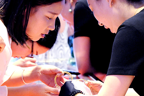 Two women admire a gold bracelet at a jewelry shop in Suzhou, Jiangsu province. (Photo/China Daily)