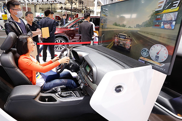 A woman plays virtual games in a car manufactured by GAC Motor Ltd during an auto expo in Beijing. (Photo/China Daily)