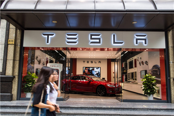 Pedestrians pass by a newly opened Tesla outlet in Shanghai in August.WANG GANG/CHINA DAILY
