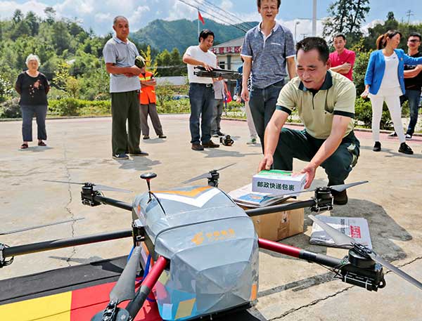 Chen Yong, a postal worker, receives packages delivered by a drone in Anji county, Zhejiang province, on Monday. Yu Lebin / For China Daily