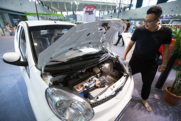 A visitor examines a new energy car at an auto exhibition in Nanjing, Jiangsu province, in early September. (Photo/China Daily)
