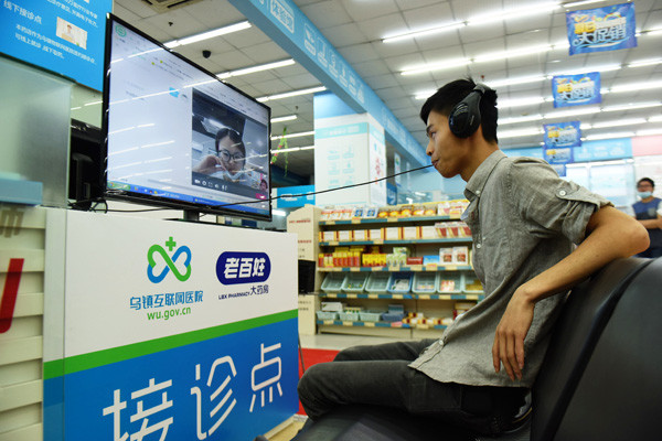 A man consults a doctor via an internet telemedicine platform at a drugstore in Hangzhou, Zhejiang province, in May. (Photo by Long Wei/For China Daily)