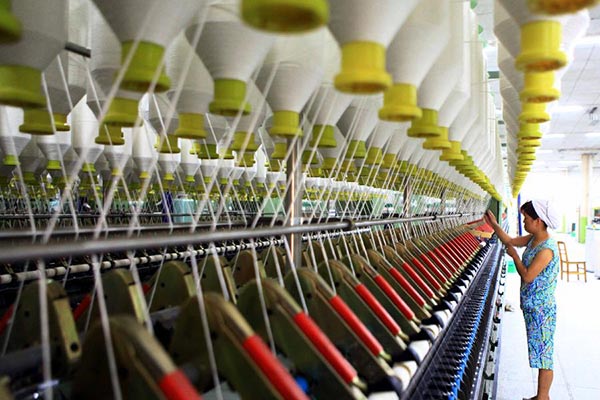 A worker operates a cotton spinning machine at a textile mill in Jiujiang, East China's Jiangxi province.(Photo/Xinhua)