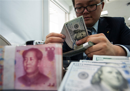 An employee at a bank counter in Nantong, Jiangsu province, counts renminbi and dollars. (Photo/China Daily)