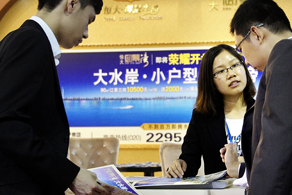 A China Evergrande salesperson introduces the property developer's apartment project to customers at a real estate expo in Guangzhou, Guangdong province. (Photo provided to China Daily)