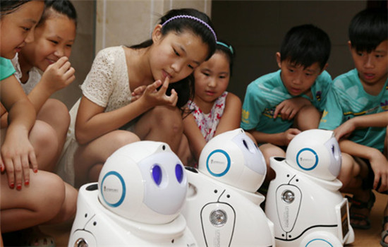 Students watch intelligent robots developed by a Beijing company for use in education, elderly care, household chores and security purposes. (Photo provided to China Daily)
