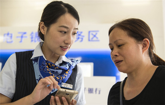An employee of China Construction Bank helps a client at a branch in Haian, Jiangsu province. CCB has set up 29 overseas branches in 27 countries and regions. (Photo by Xu Jinbai/For China Daily)