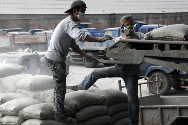 Workers offload cement bags at a factory in Huaibei, Anhui province. (Photo by Wu He/For China Daily)